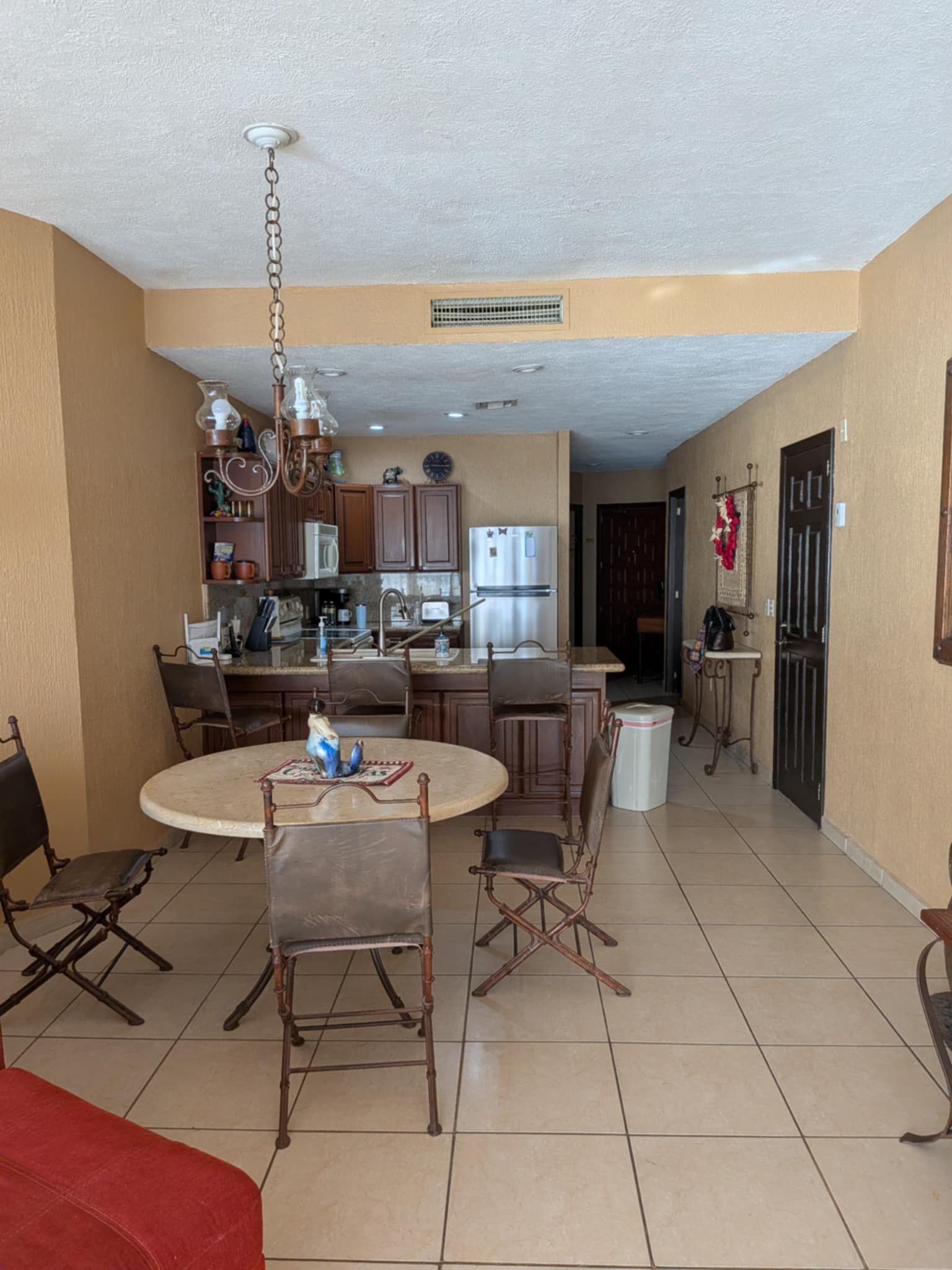 Dining table beside a full kitchen with refrigerator, stove and breakfast bar